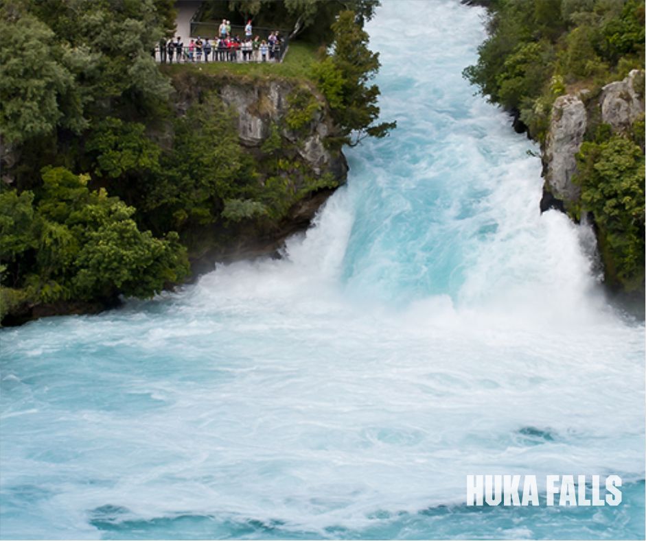 Stunning view of Huka Falls in New Zealand, showcasing the powerful waterfall and crystal-clear turquoise water surrounded by lush greenery.